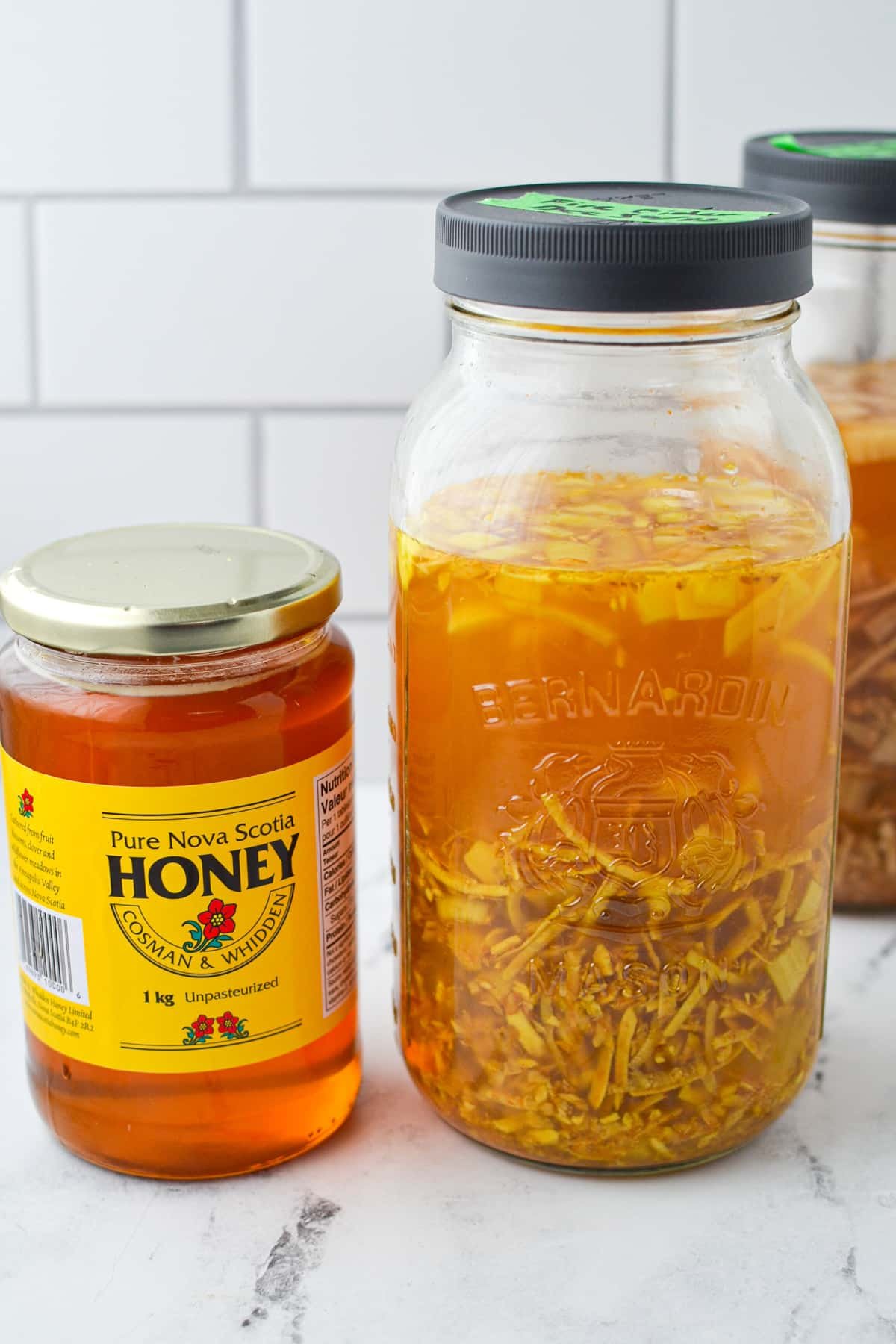 A large mason jar with fire cider next to a jar of honey.