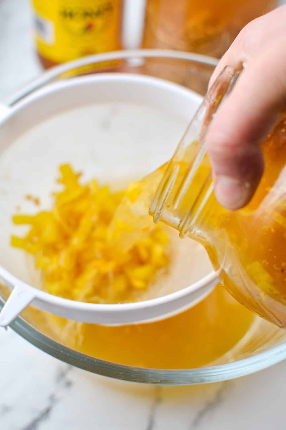 Straining infused vinegar through a strainer.