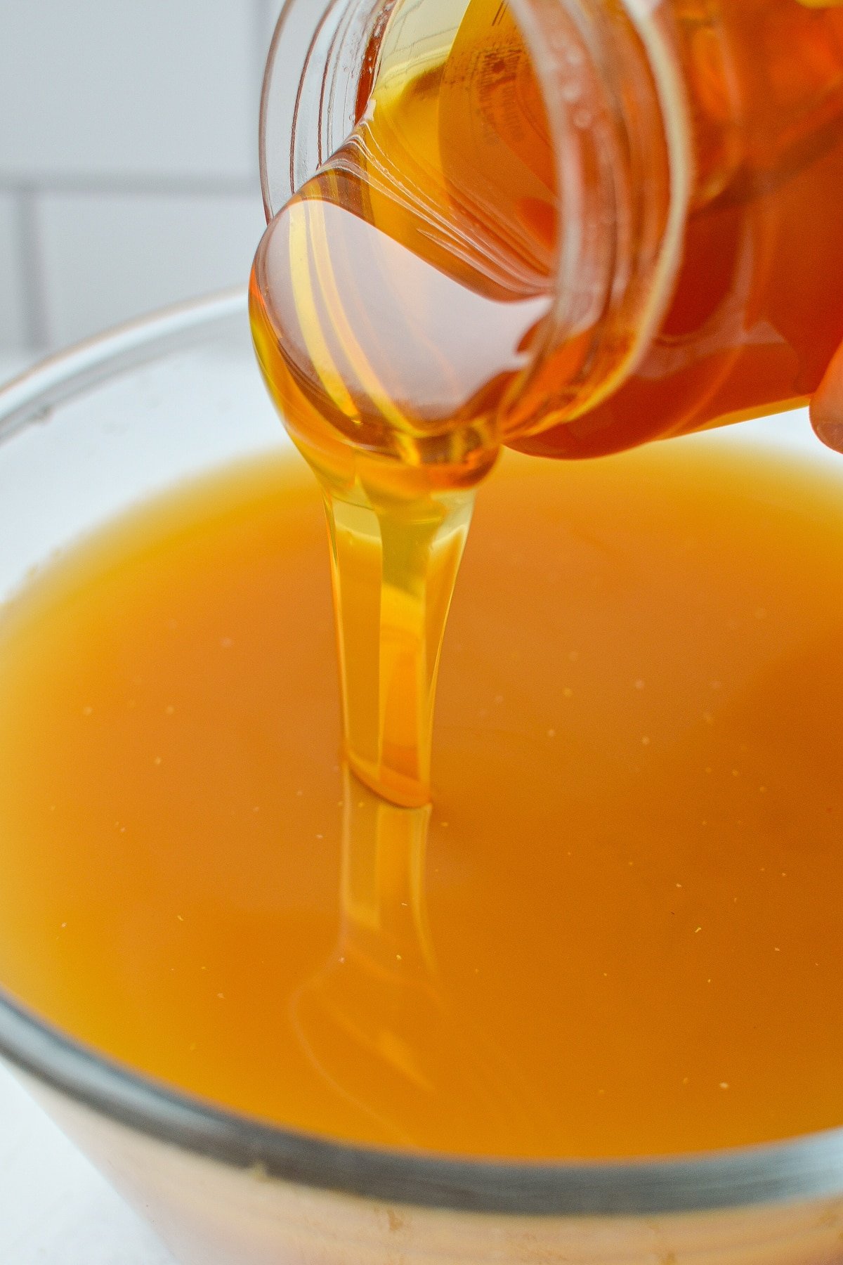 Adding honey to a large bowl of infused vinegar.