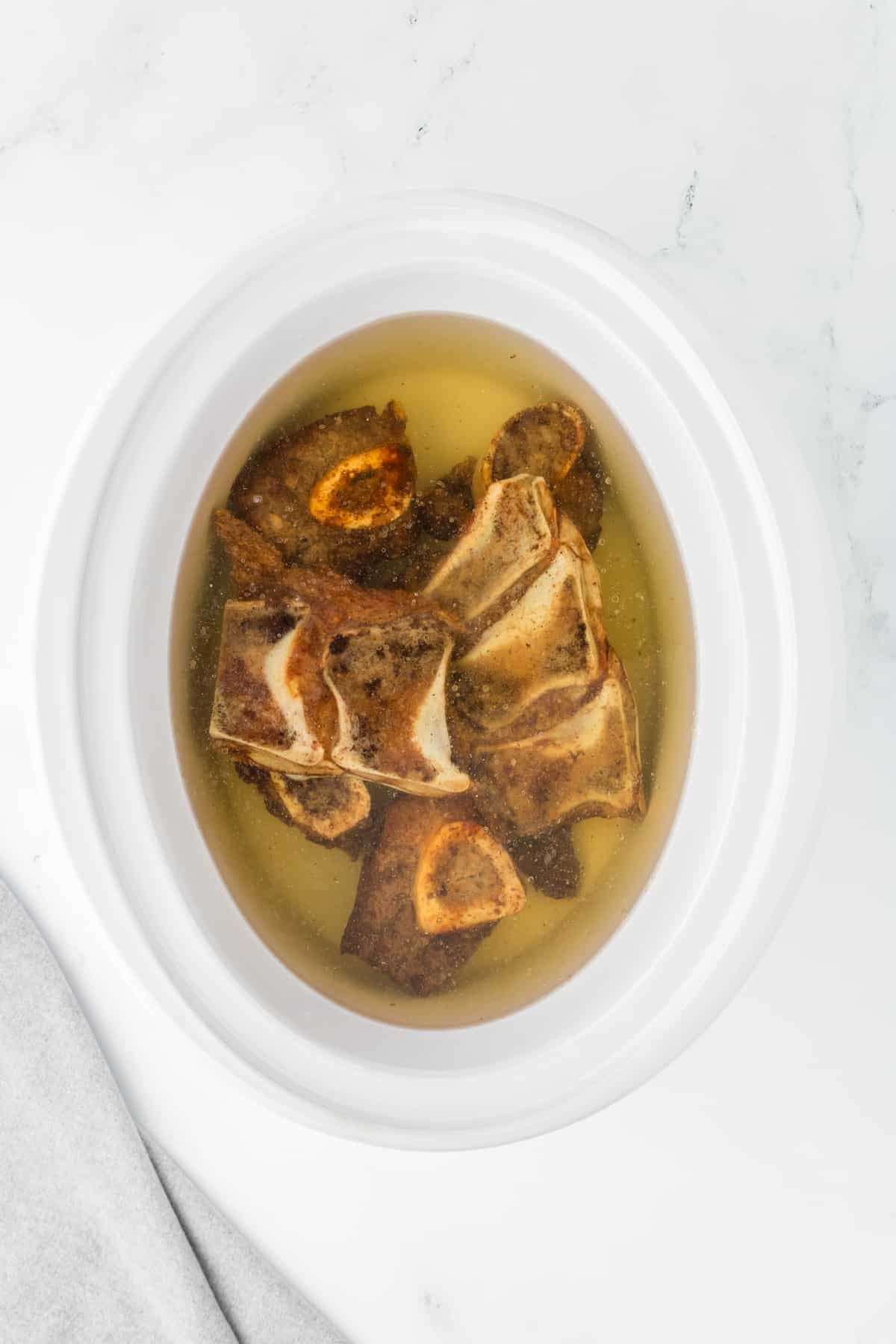 Beef bones in a slow cooker, covered with water.