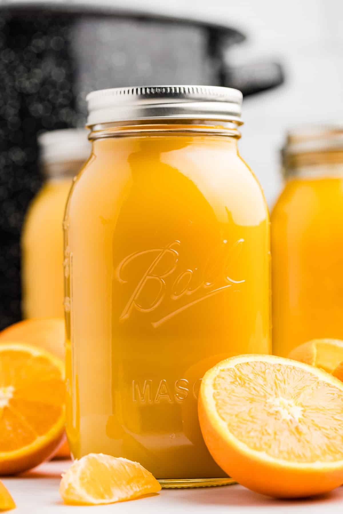 A quart jar filled with orange juice, with a water bath canner in the background.