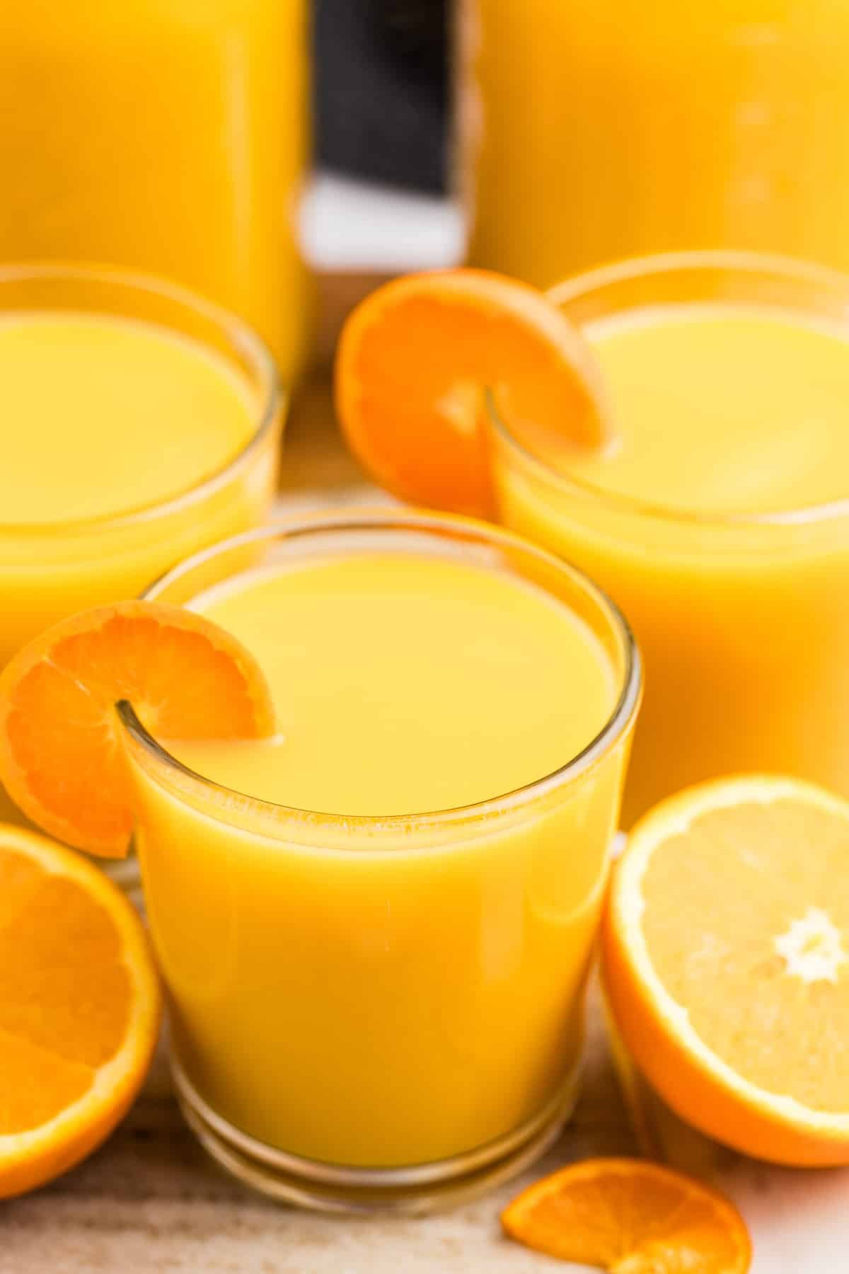 Glasses filled with orange juice and garnished with orange slices.