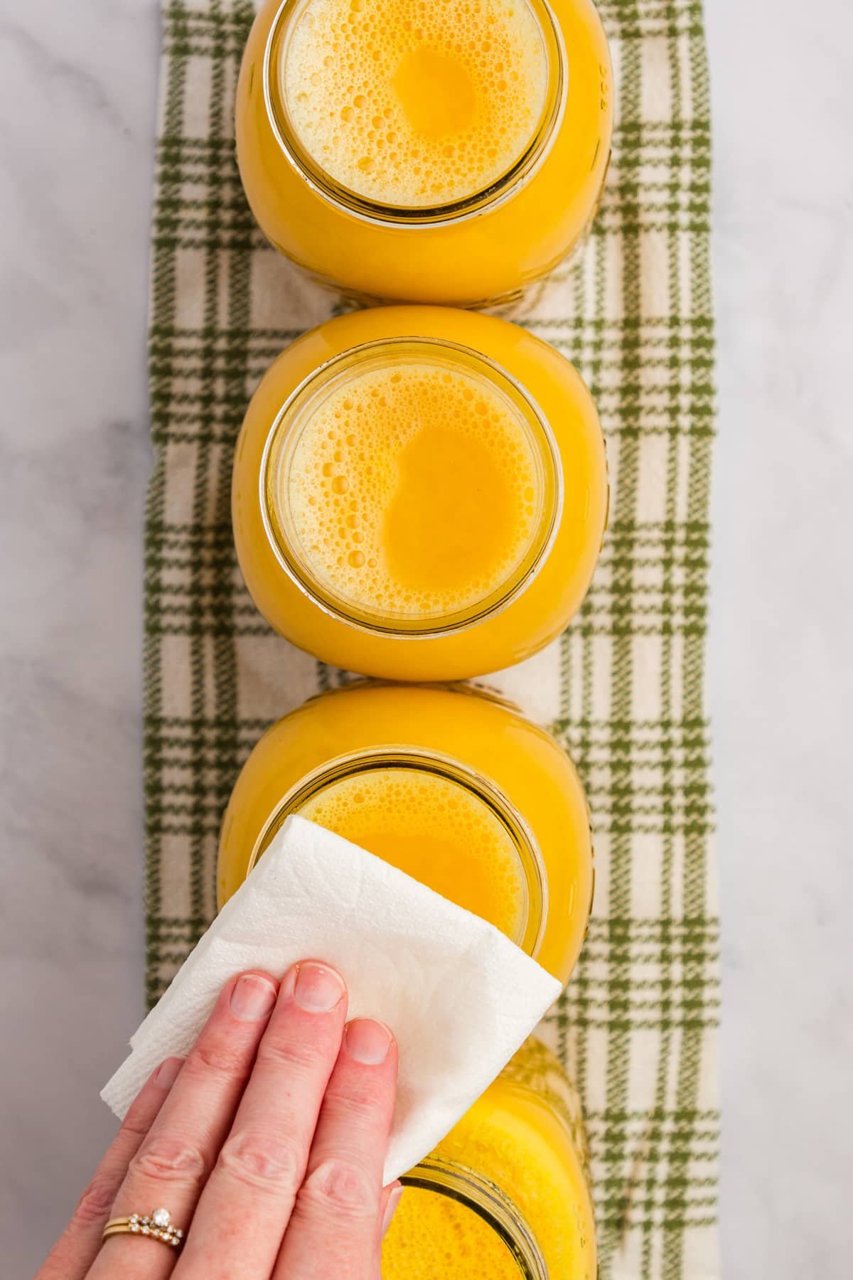 Wiping canning jar rims with a paper towel.