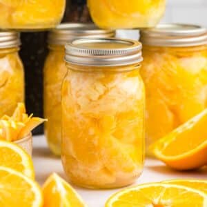 A jar of home canned orange segments, with other jars in the background.