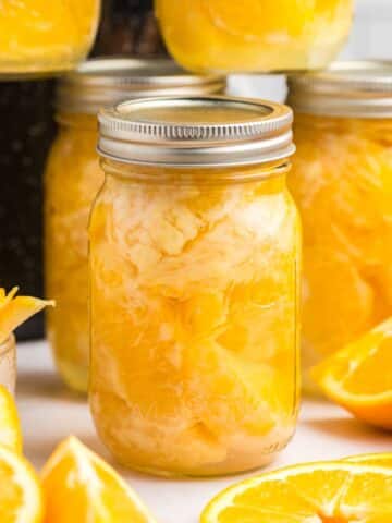 A jar of home canned orange segments, with other jars in the background.