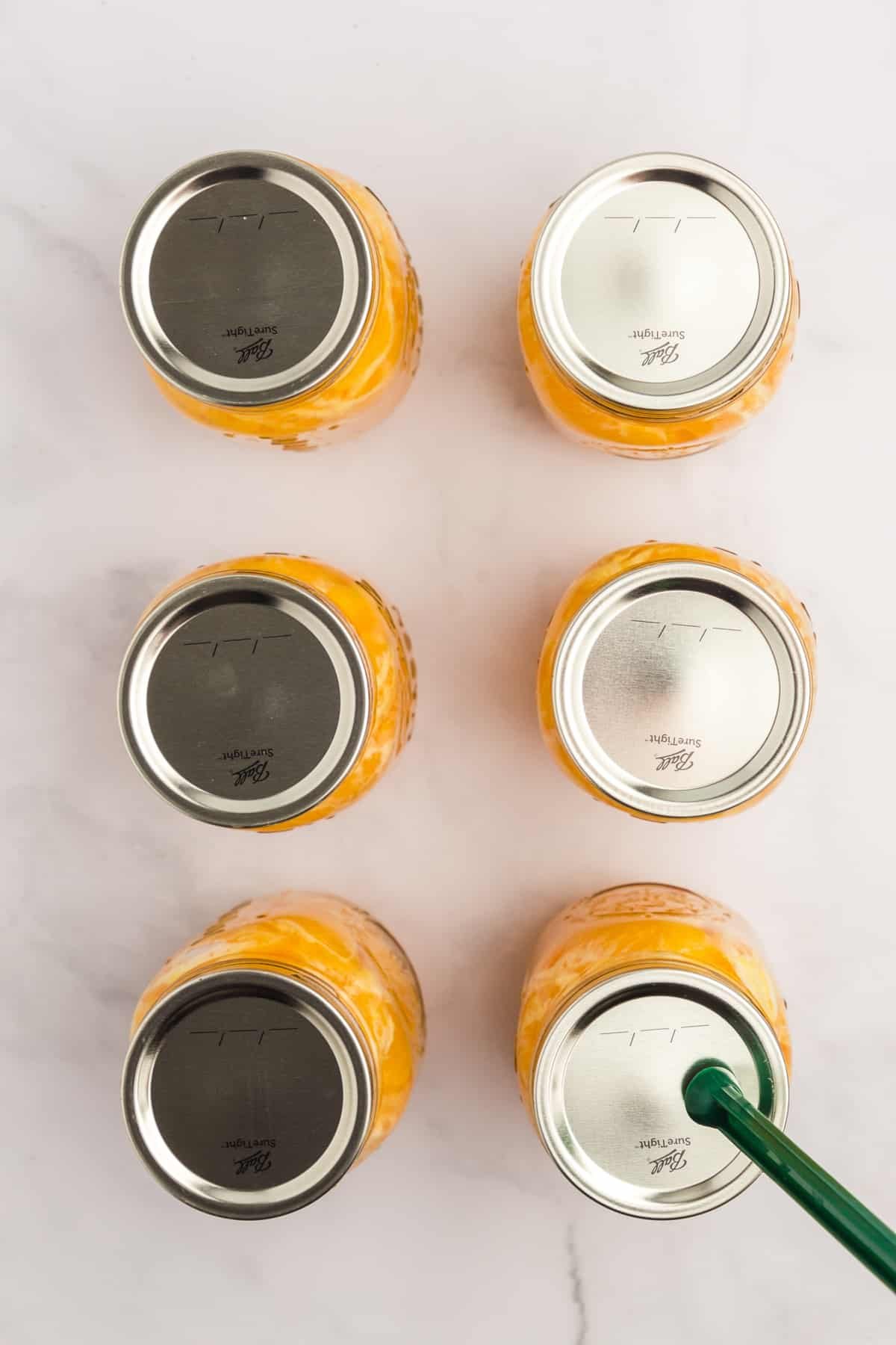 Placing a canning lid on a jar using a magnetic lid lifter.