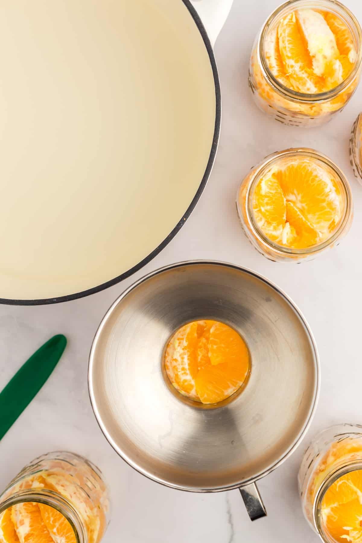 Adding syrup over a jar of orange segments.
