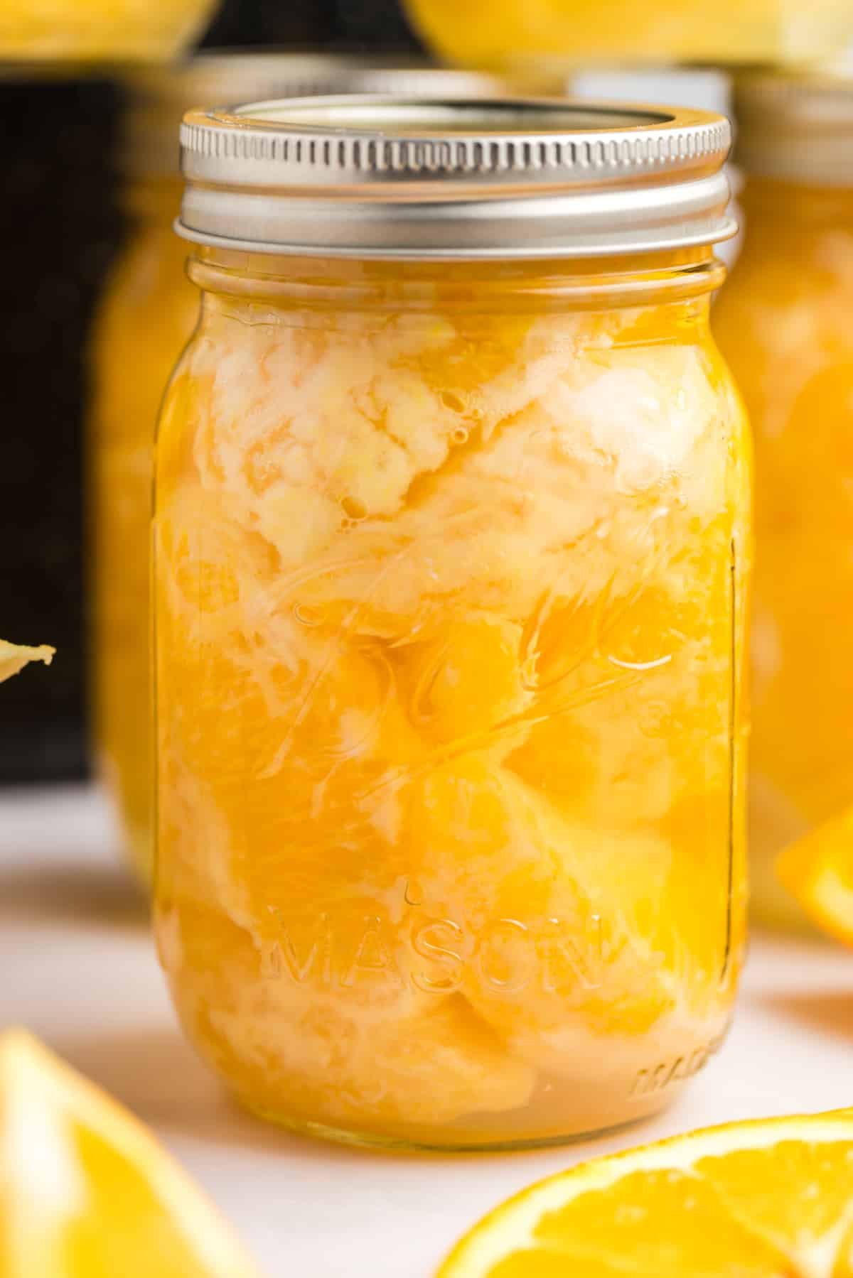 A canning jar filled with citrus segments and syrup.