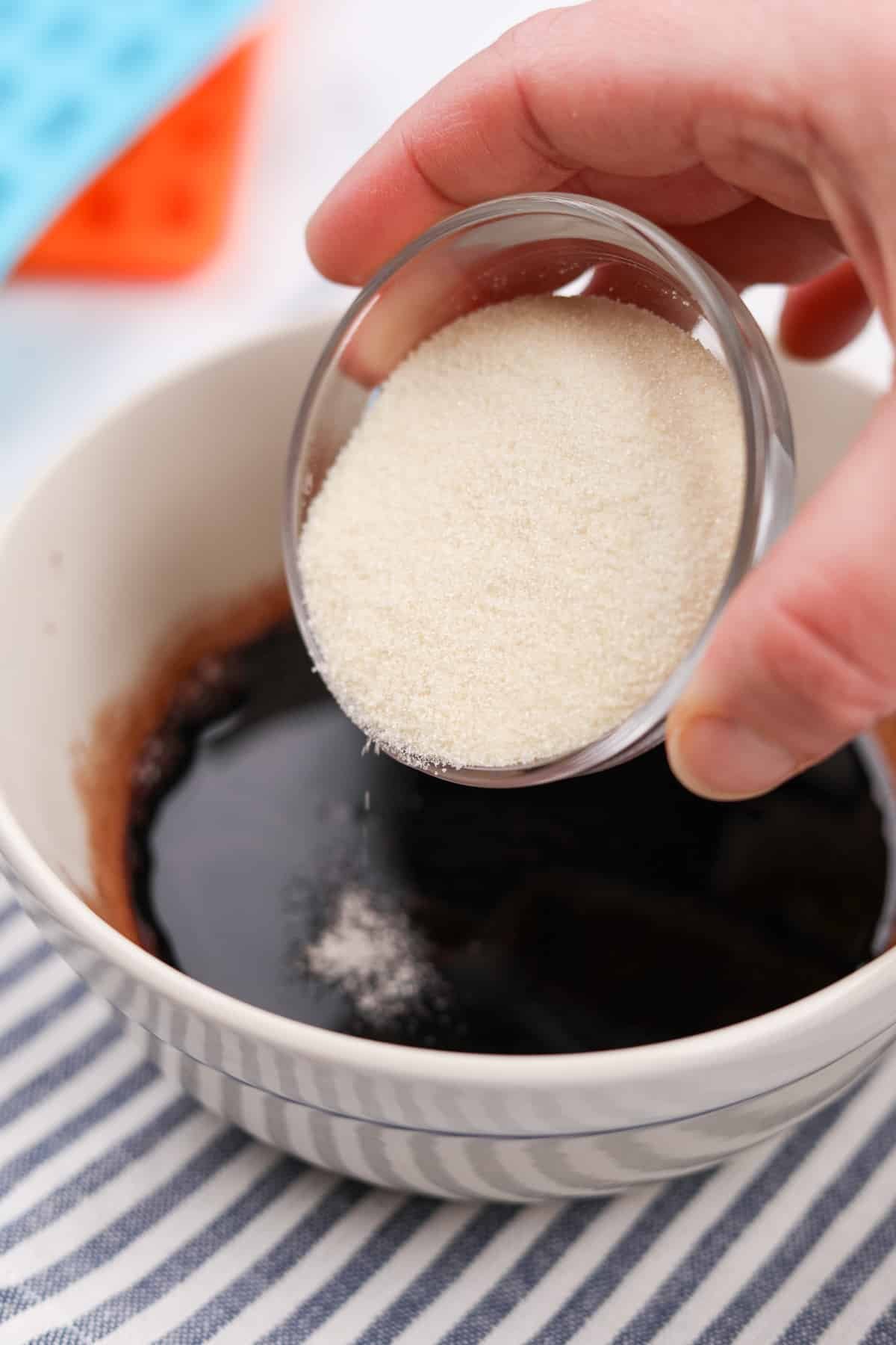 Sprinkling beef gelatin into a small bowl of liquid.