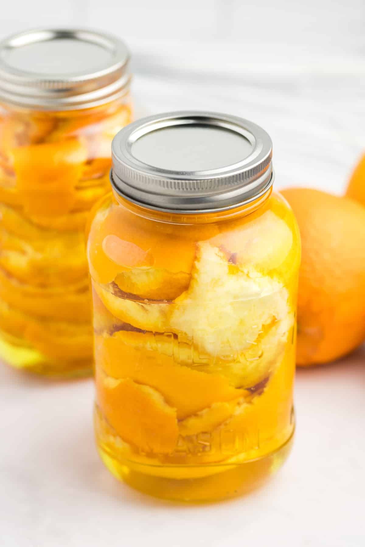 A large jar filled with orange peels and vinegar.