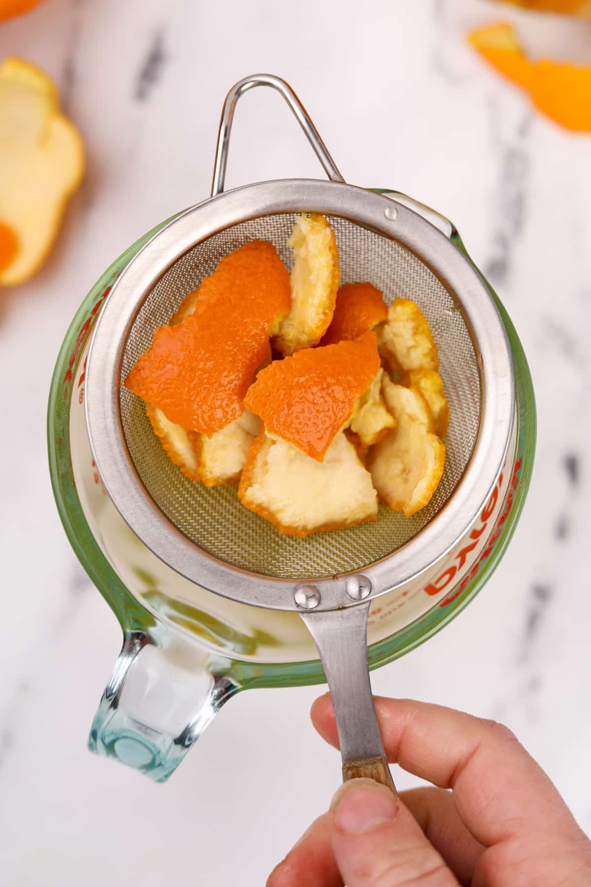 A strainer with spent orange peels in it.