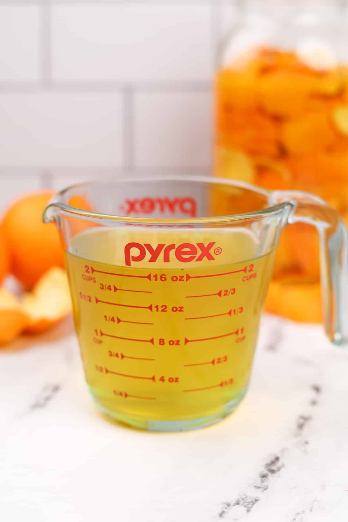 A measuring cup filled with orange colored vinegar.