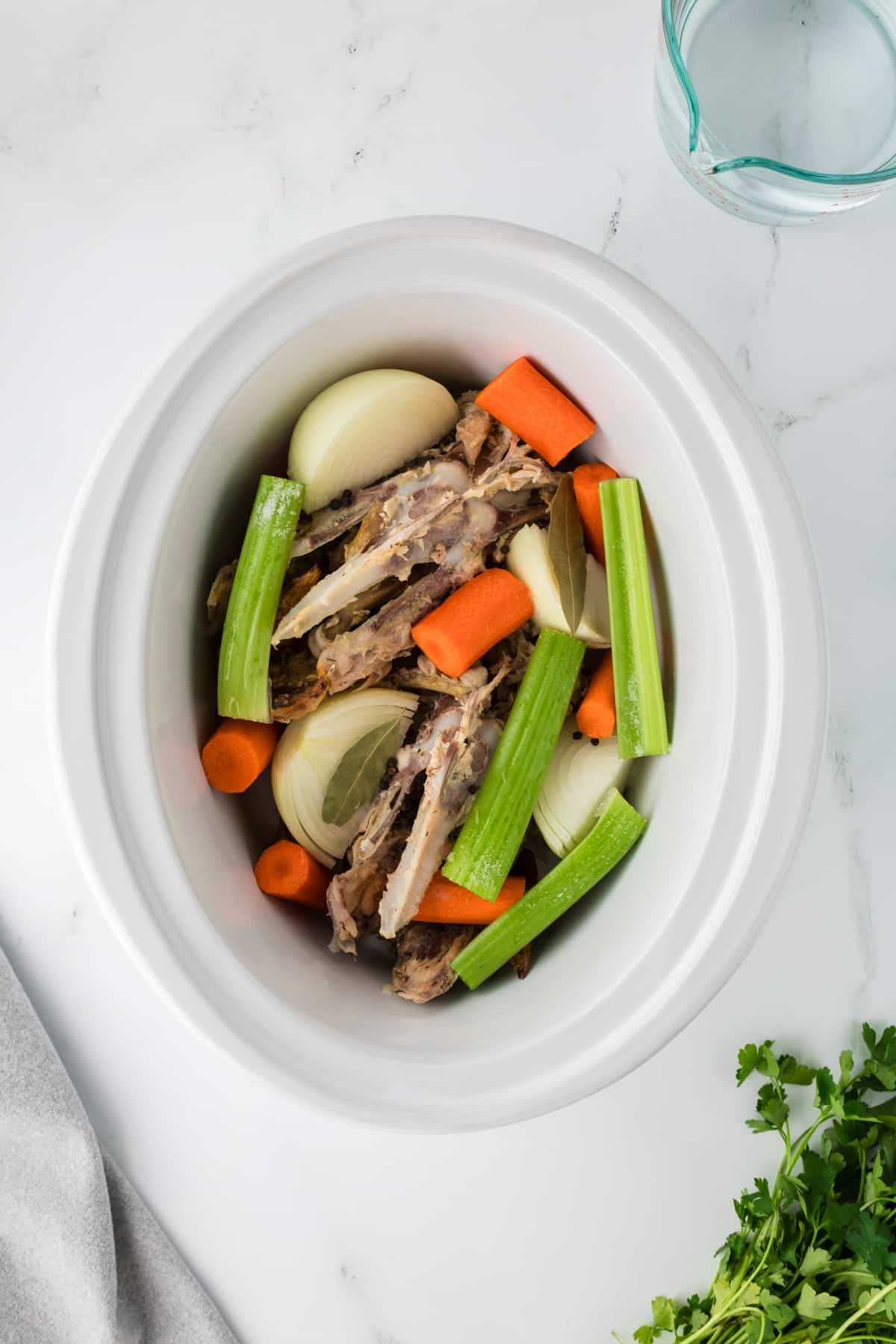 A slow cooker filled with bones and vegetables.