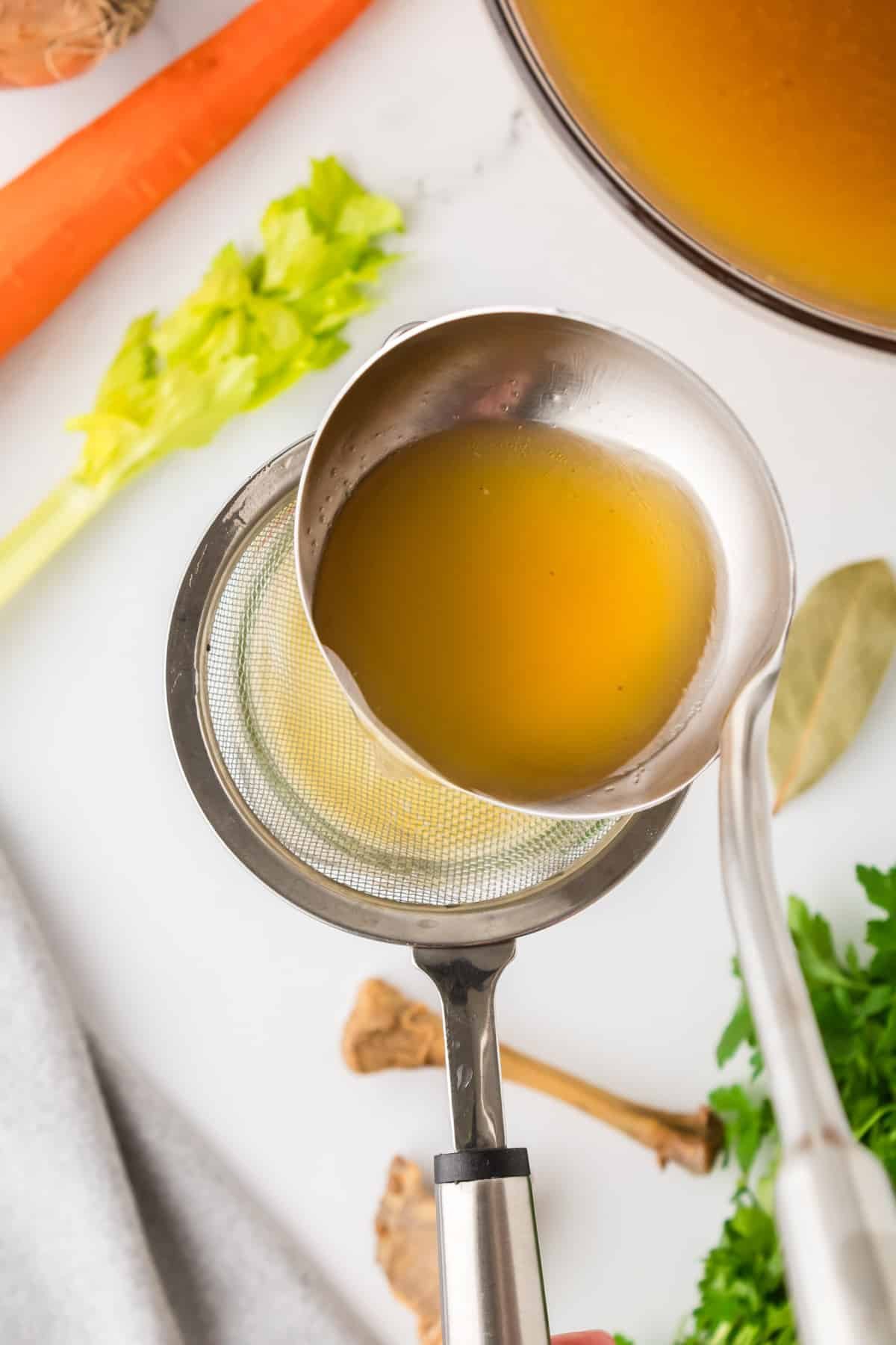 Ladling broth through a strainer.