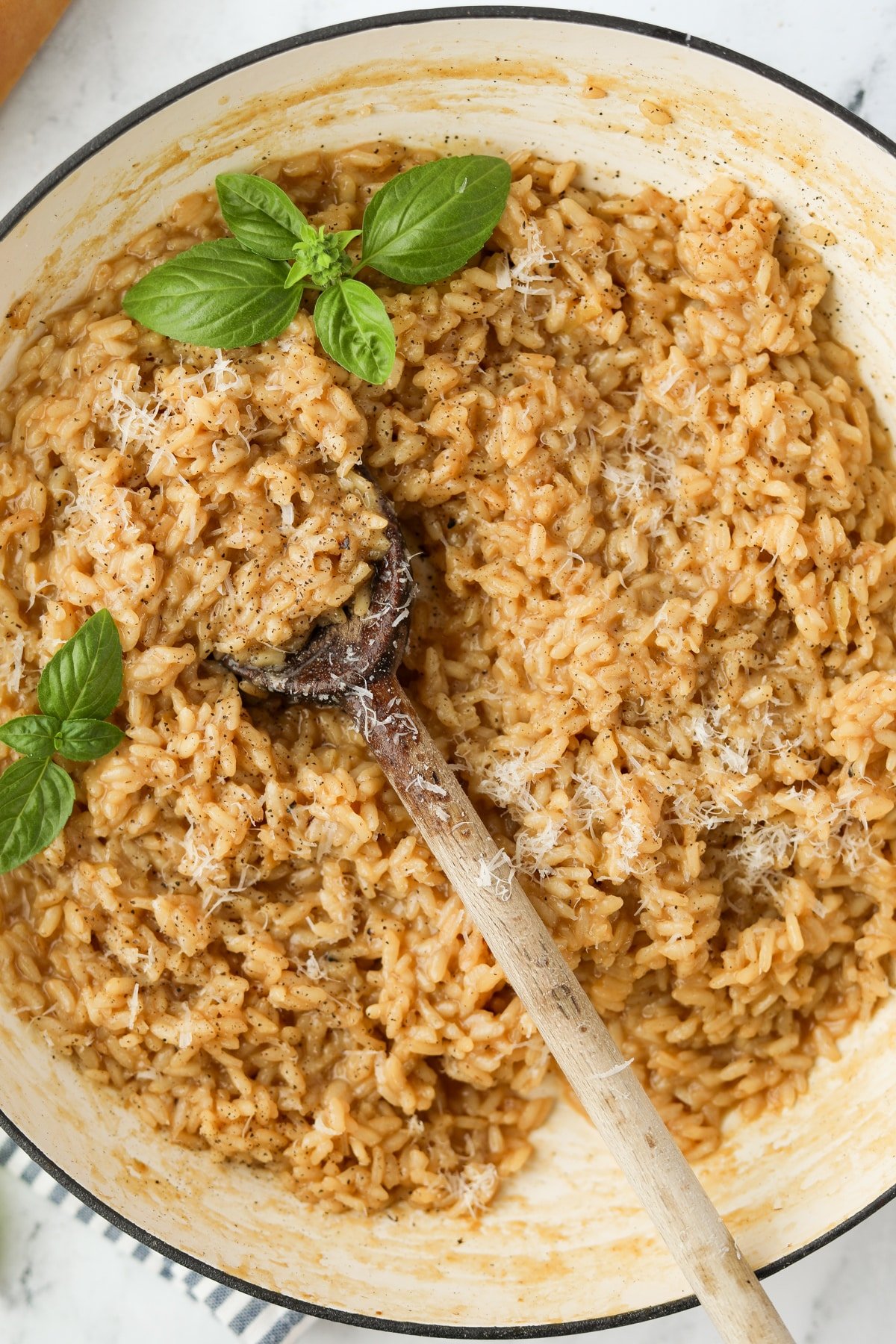 An enameled skillet filled with cooked rice and garnished with fresh basil.