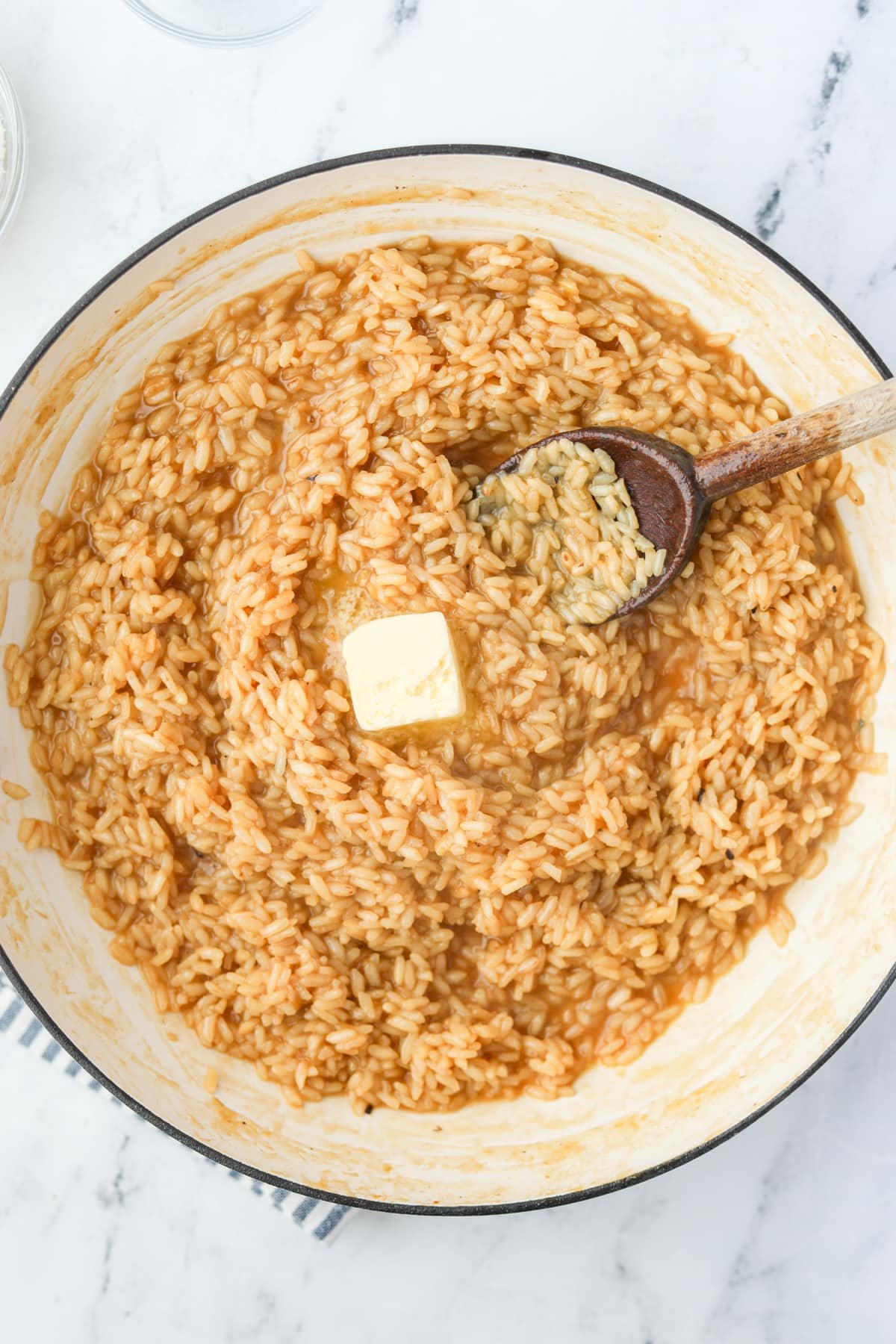 A skillet filled with risotto and topped with a pat of butter.