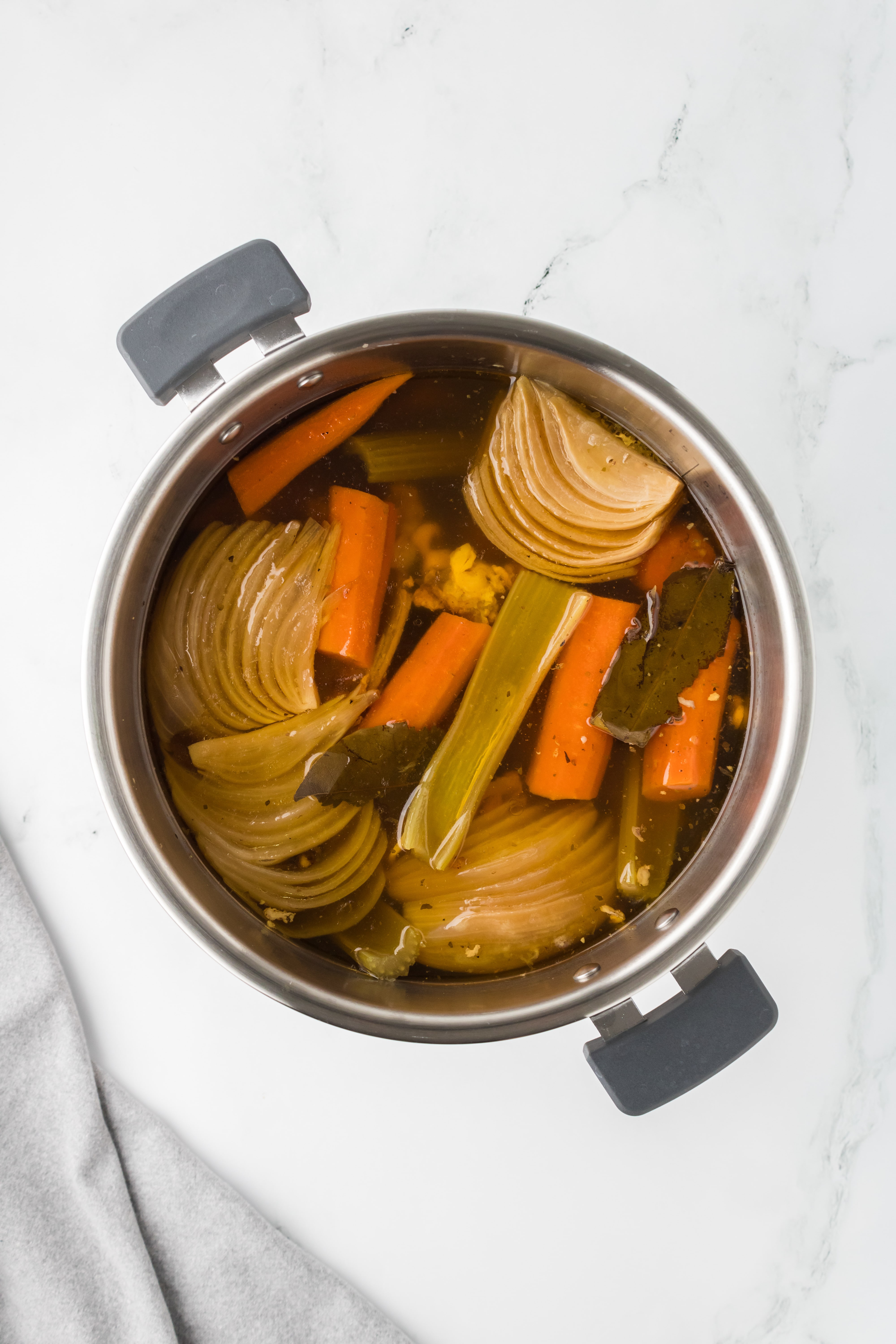 An Instant Pot filled with broth with floating cooked vegetables in it.