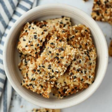 A small bowl filled with sourdough crackers topped with everything bagel seasoning.