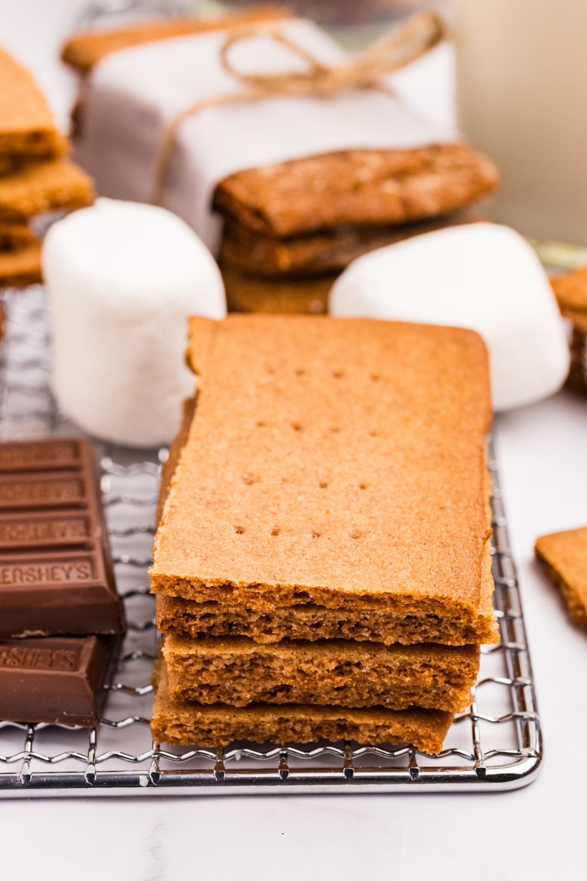 A stack of graham crackers surrounded by marshmallows and chocolate squares.