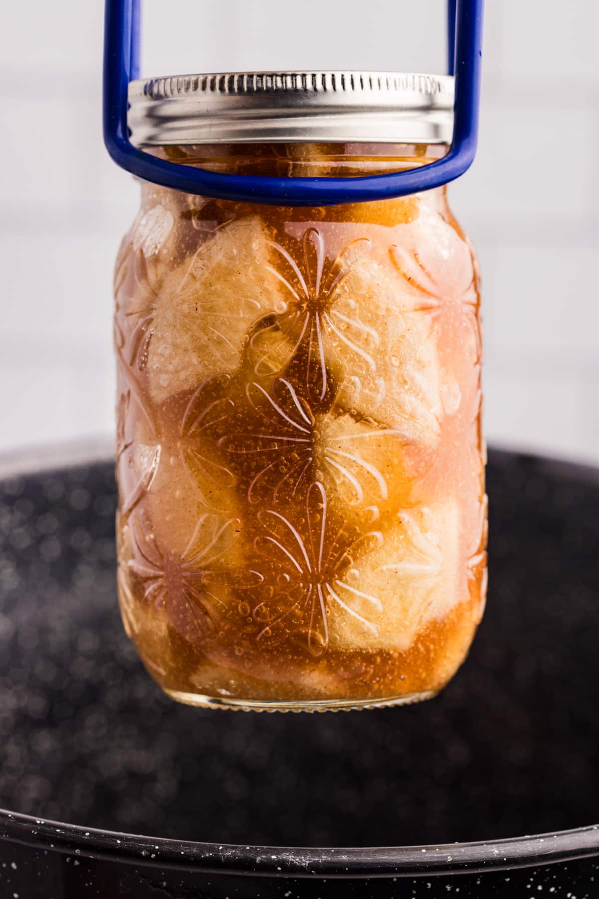 Lifting a jar of home canned pie filling from a water bath canner.