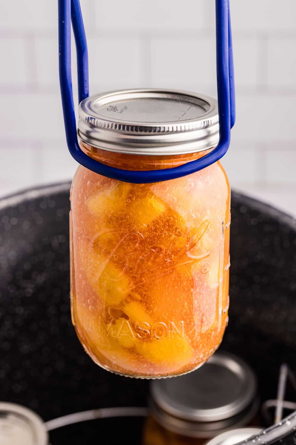 Removing a jar of peach pie filling from a water bath canning.