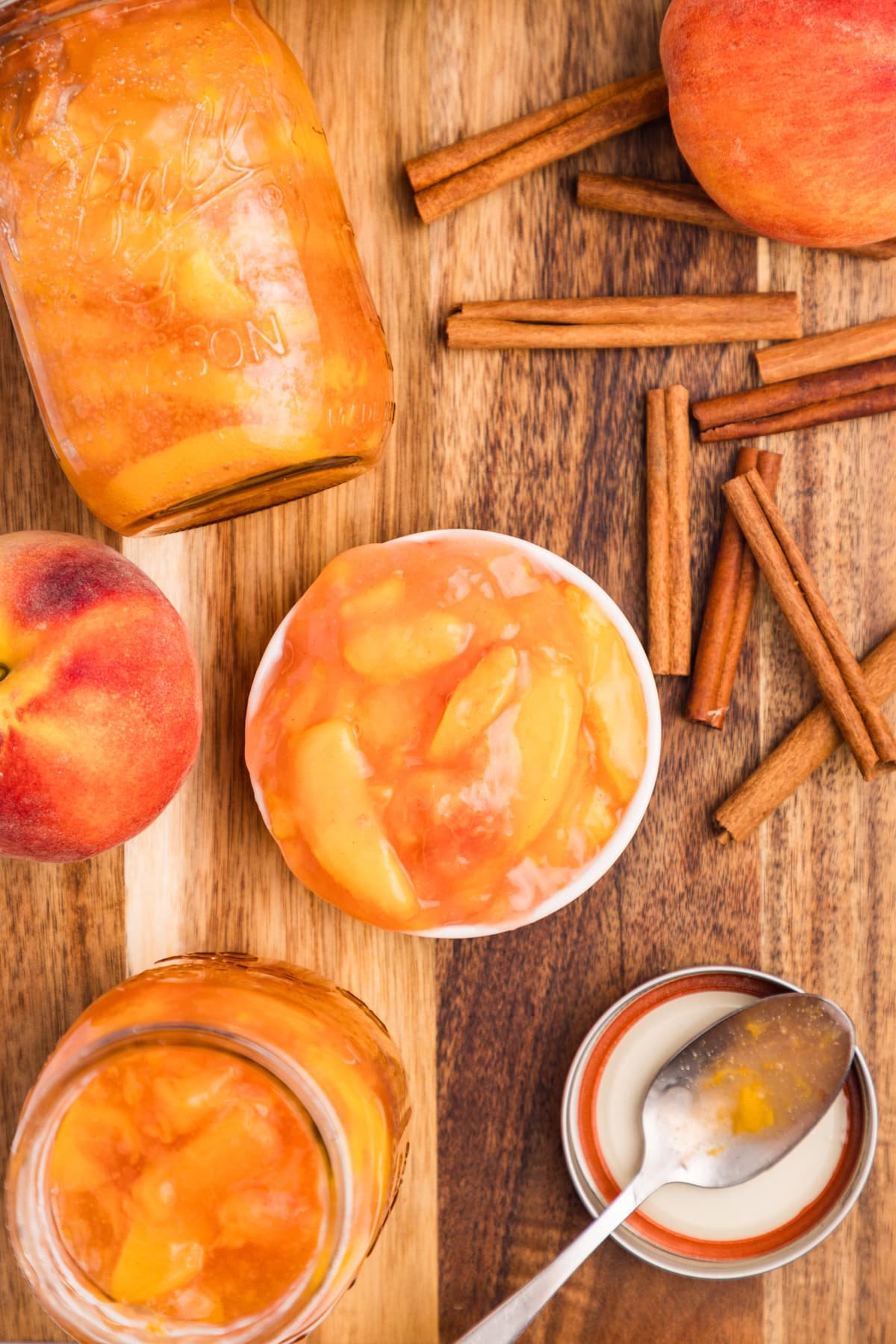 An overhead view of a small bowl filled with preserved pie filling, with jars surrounding it.