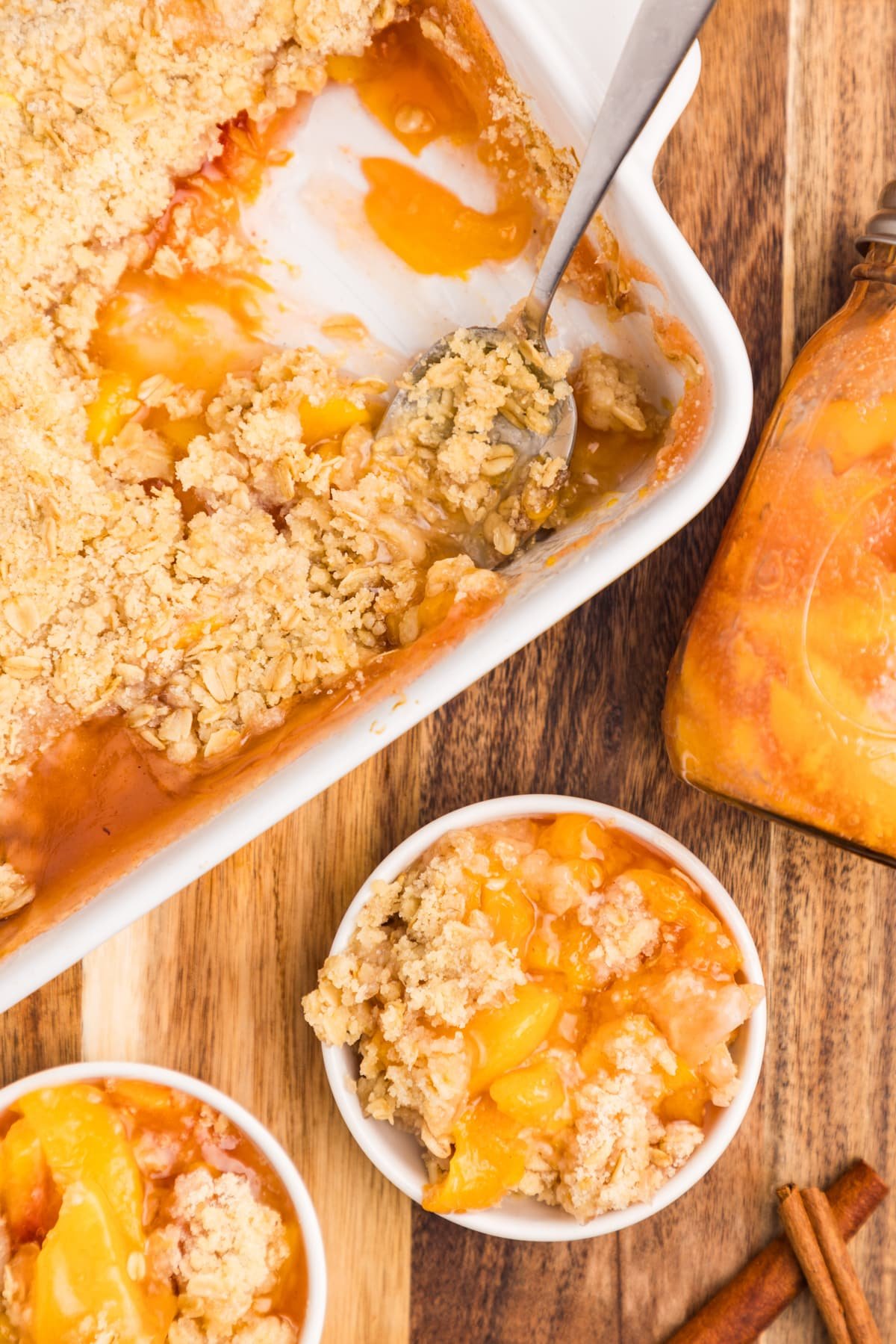 A peach crisp with a large spoon resting inside the dish.