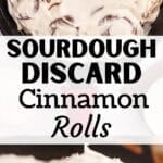 A cast iron pan filled with cinnamon rolls and topped with cream cheese frosting.