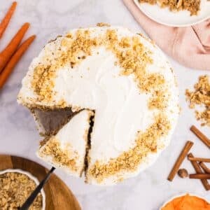 A large carrot cake with two slices cut from it.