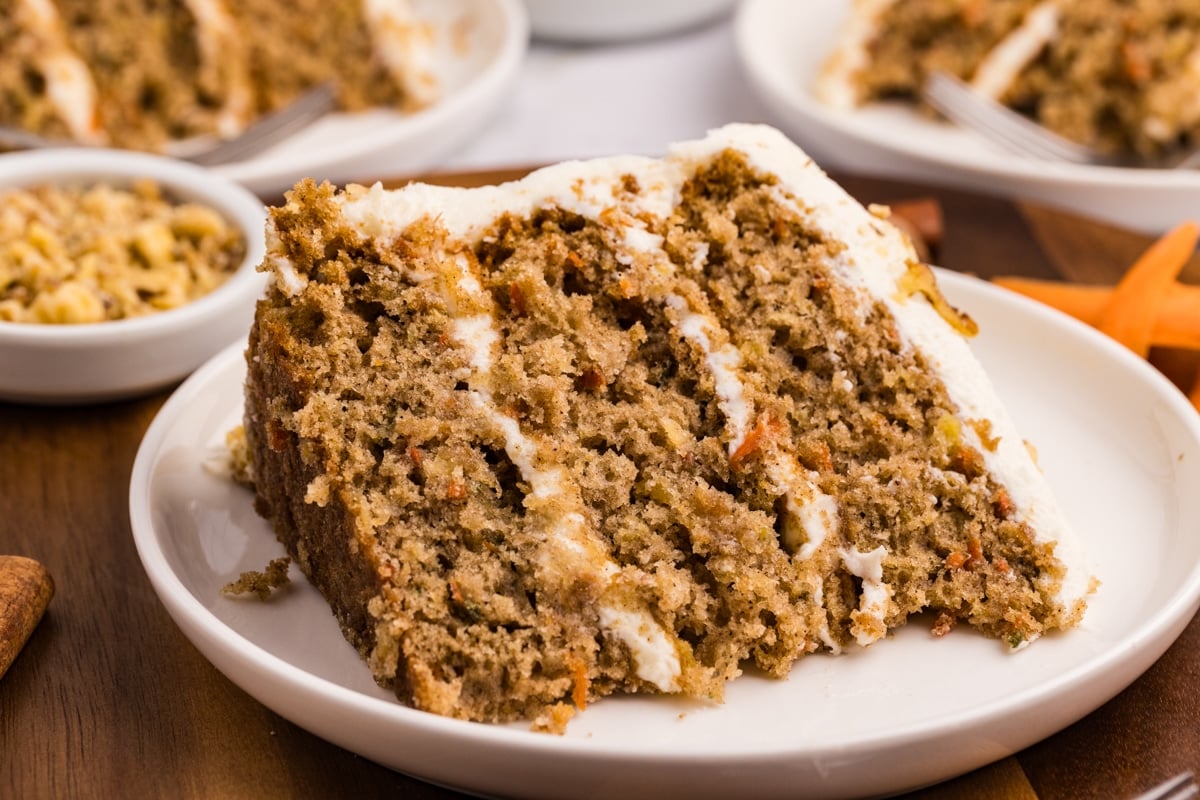 A slice of carrot cake on a plate, showing the various layers.