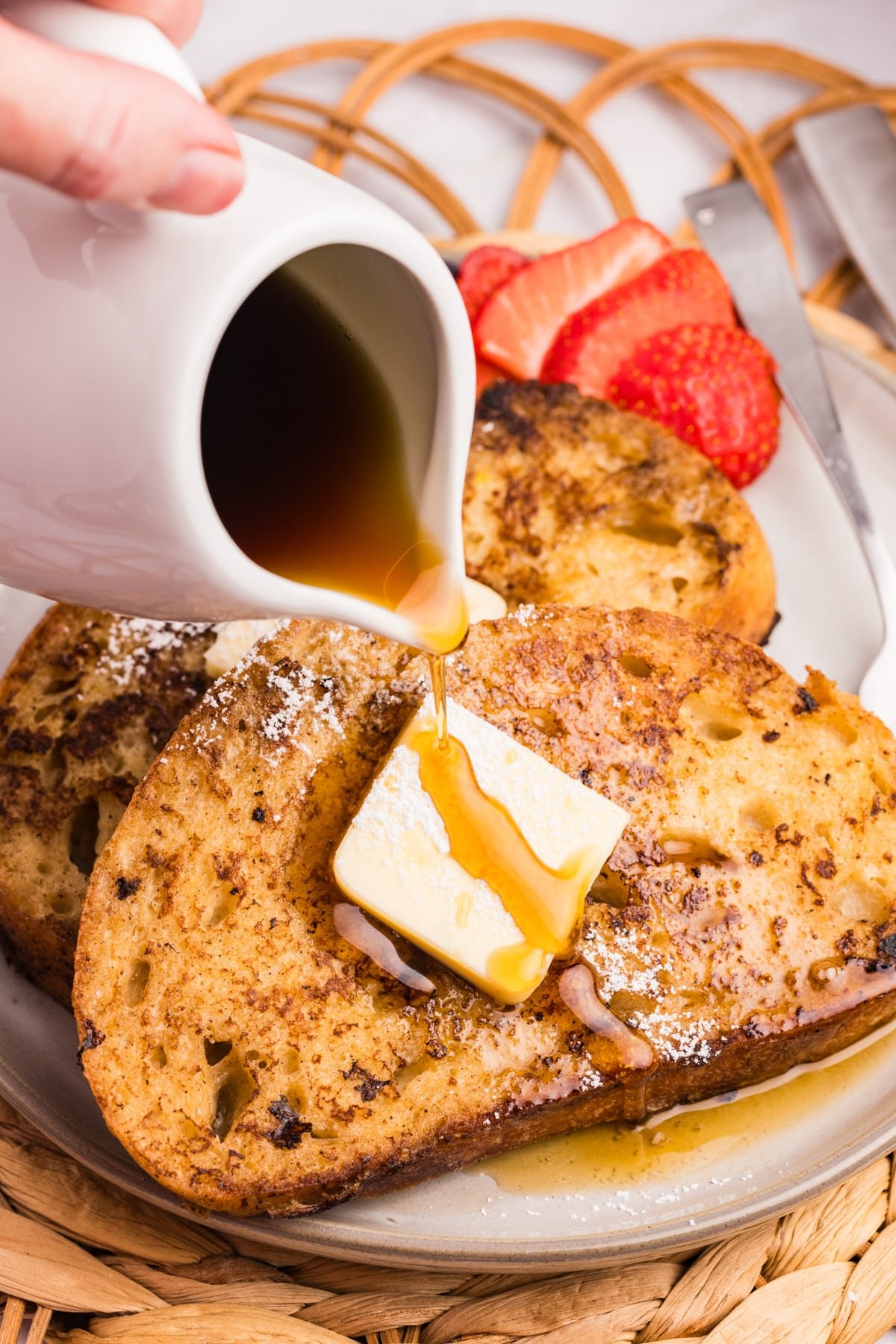 Pouring maple syrup over a stack of french toast.