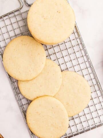 Round sourdough sugar cookies resting on a wire rack.
