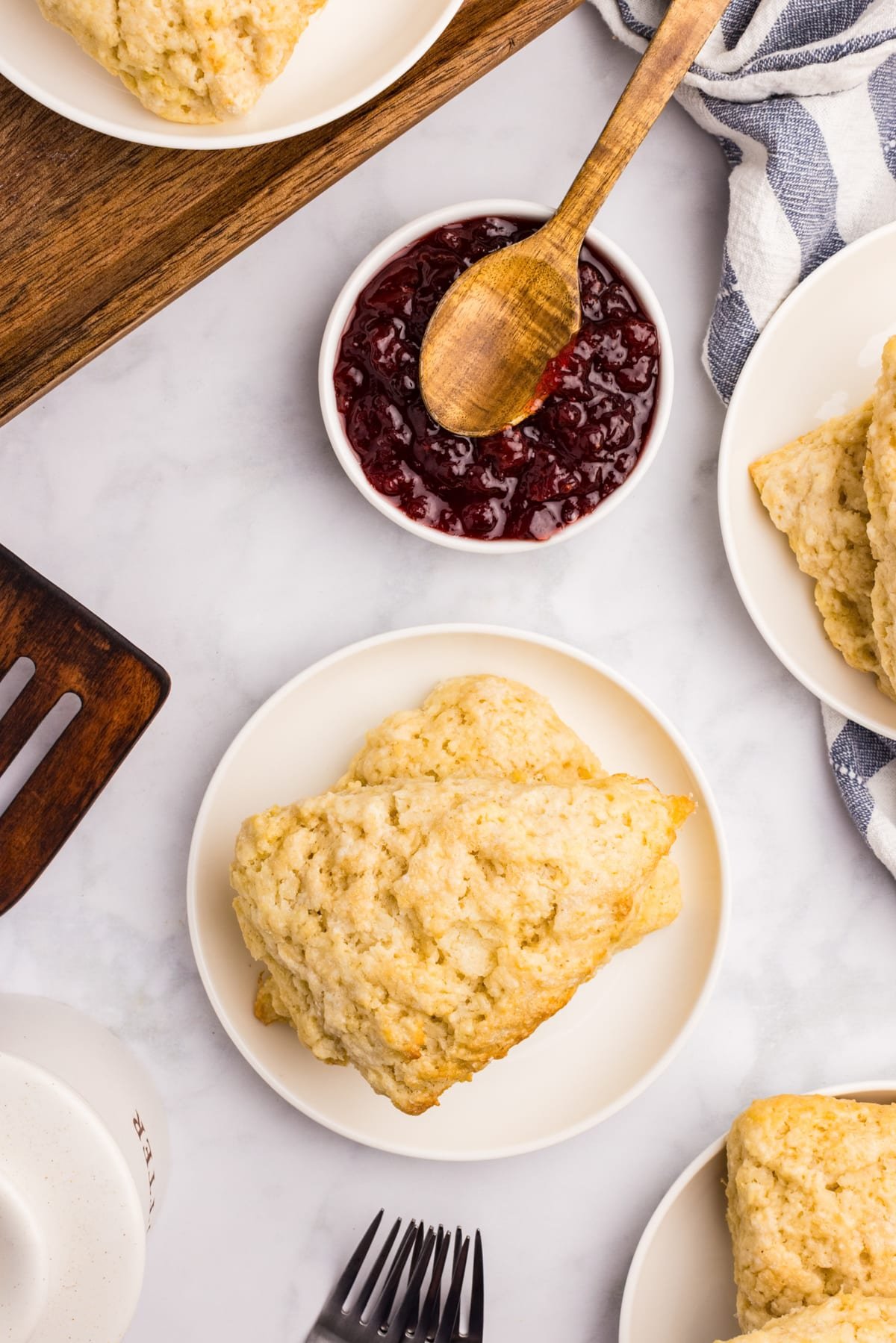 Scones on a white plate with a bowl of jam on the side.