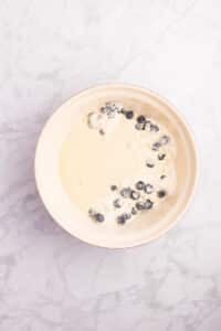 Adding wet ingredients to the dry, with fresh blueberries.