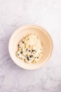 A soft, shaggy scone dough in a bowl with fresh blueberries.