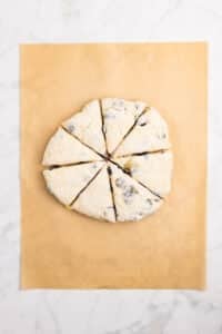 A round of dough cut into 8 wedges on a sheet of parchment paper.