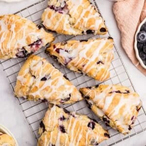 Blueberry scones on a wire rack, drizzled with lemon glaze.