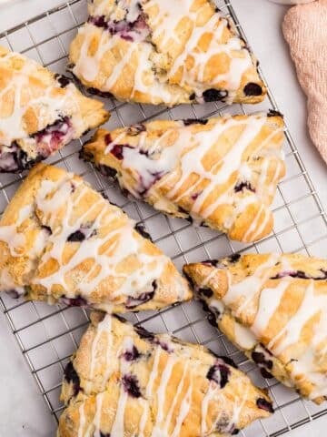Blueberry scones on a wire rack, drizzled with lemon glaze.