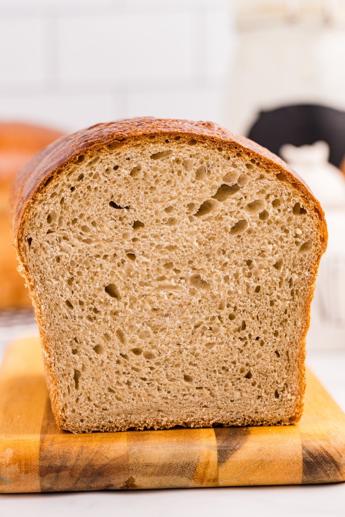 A loaf of sourdough bread on a wooden cutting board, cut and showing the crumb.