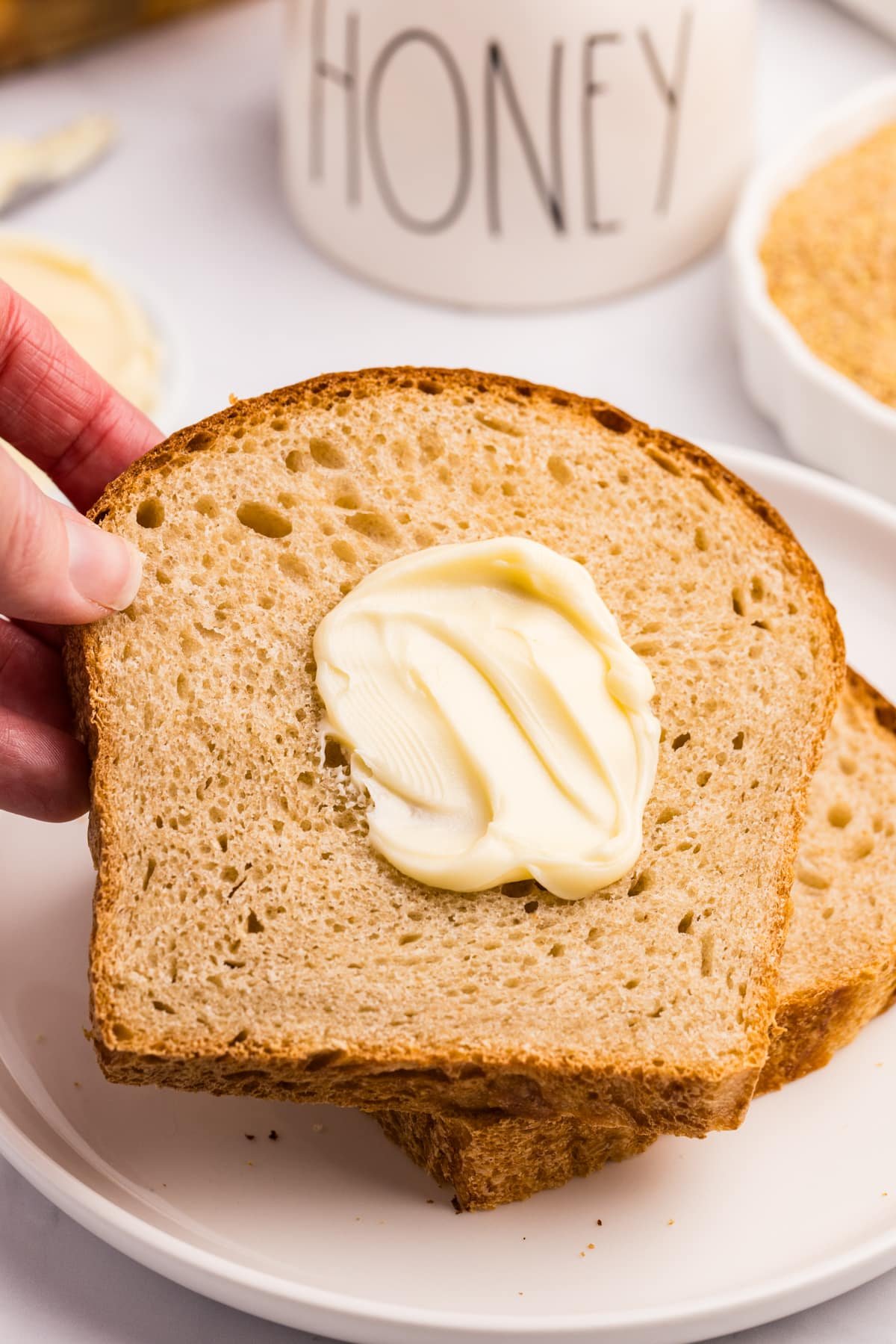 A slice of whole wheat bread with a pat of butter on it.