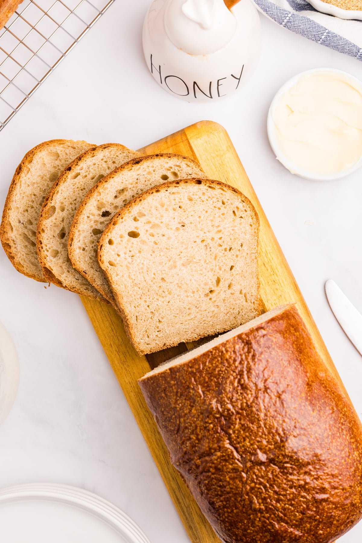 A loaf of whole wheat bread, cut into slices on a wood cutting board.