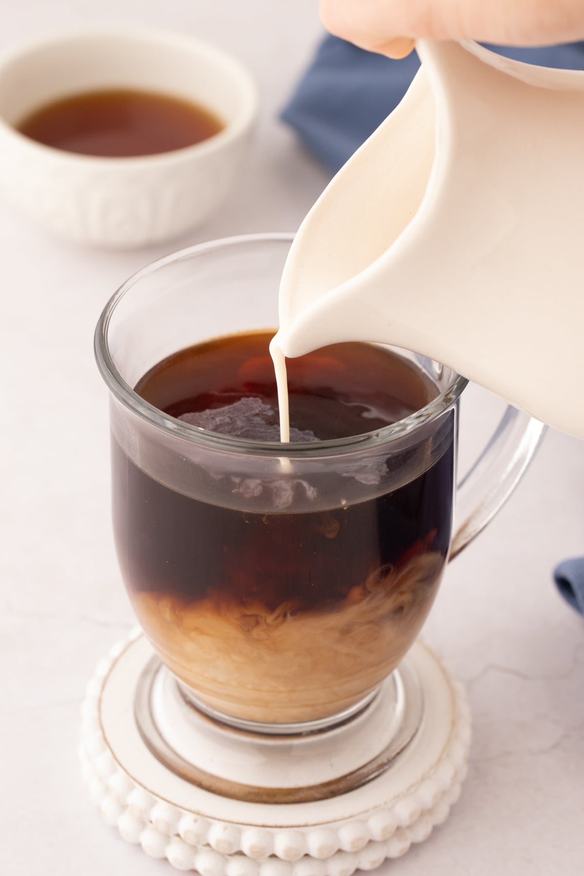 Pouring coffee creamer into a cup of hot coffee.