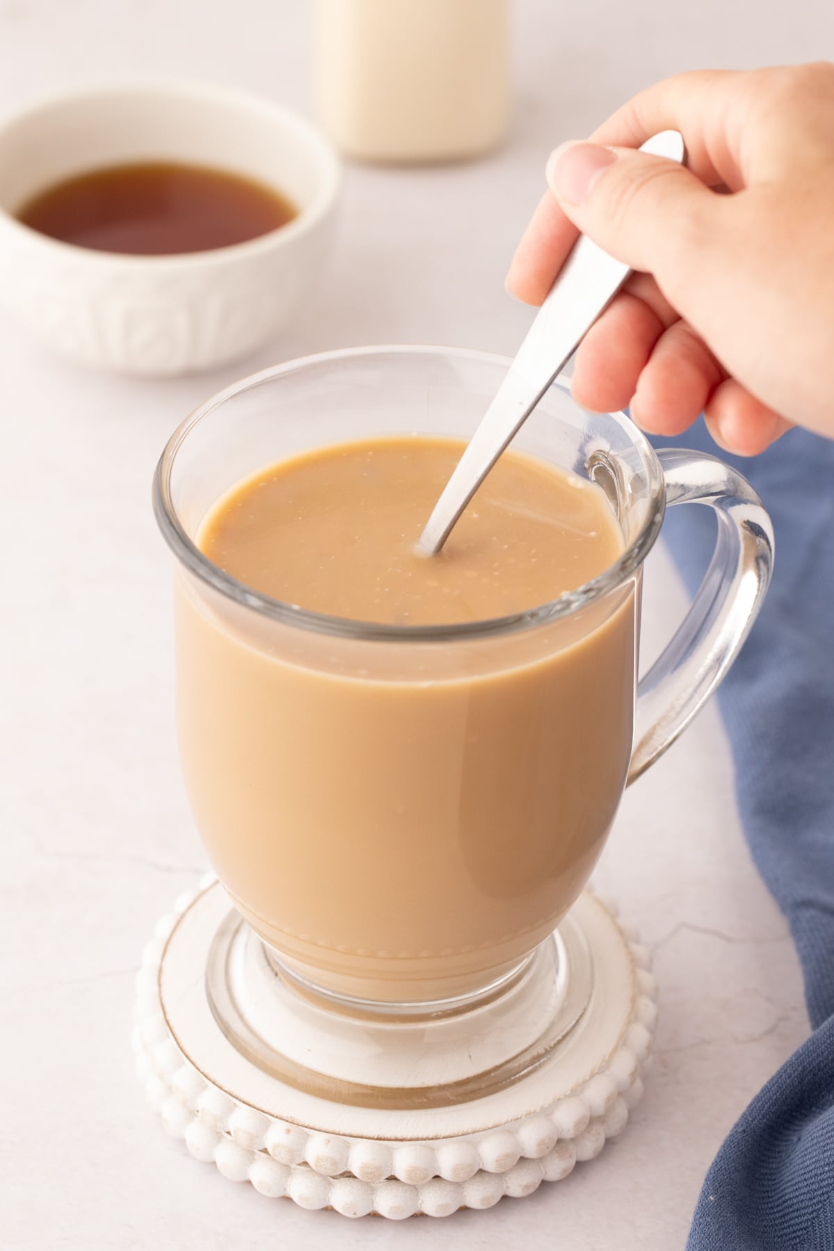 A cup of coffee being stirred with a spoon.