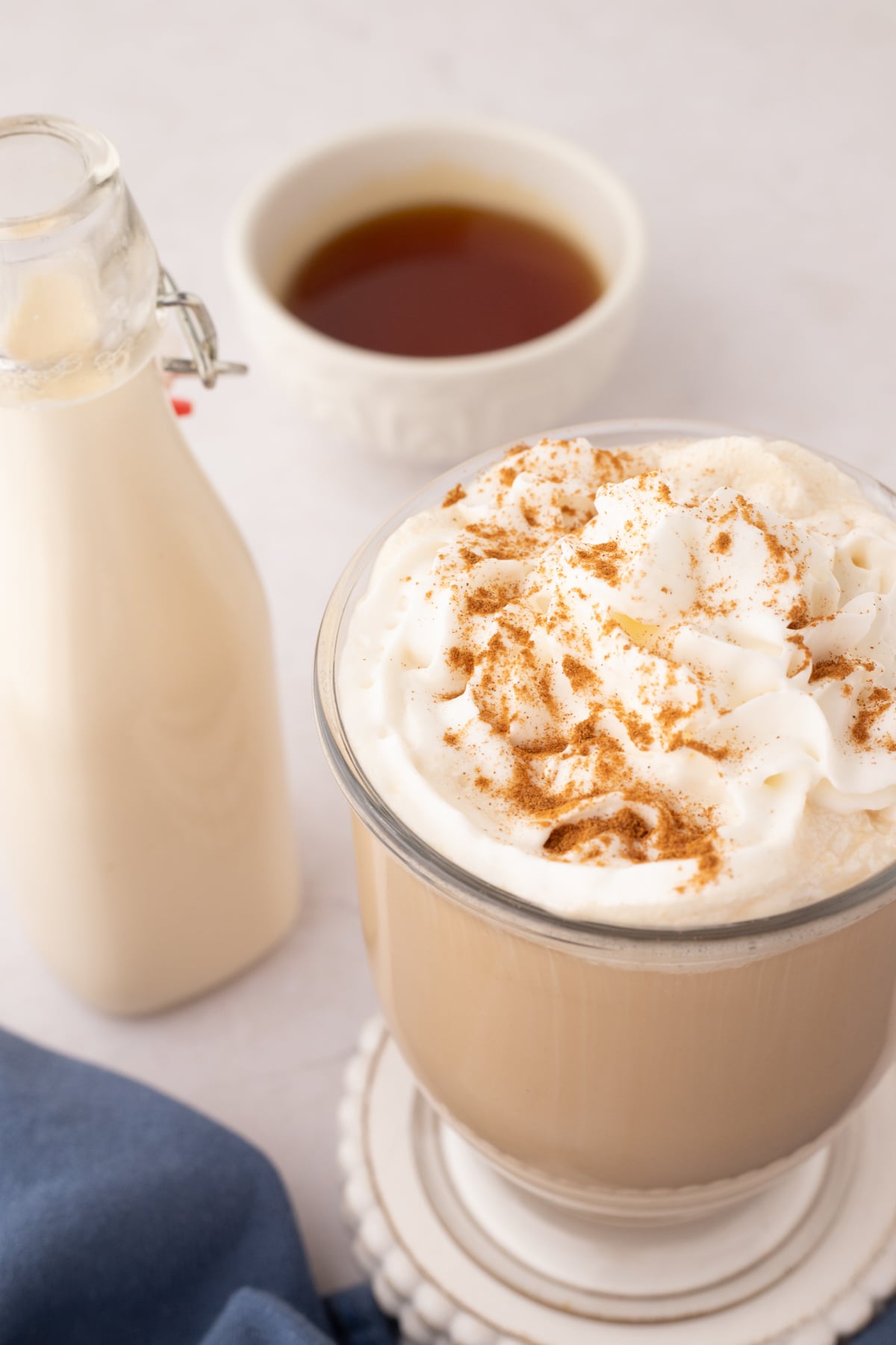 A cup of coffee topped with whipped cream and a sprinkle of cinnamon.
