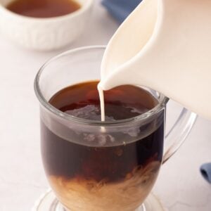 Pouring coffee creamer into a cup of coffee.