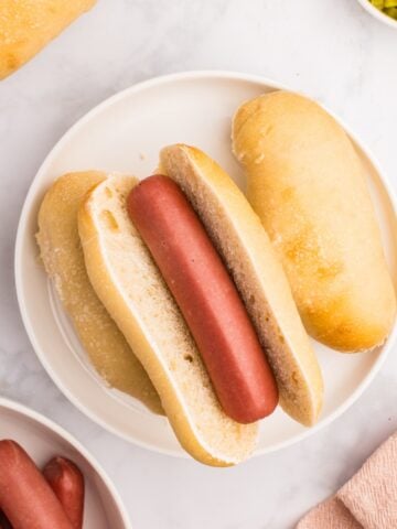 A homemade sourdough hot dog bun with a cooked hot dog in the center.