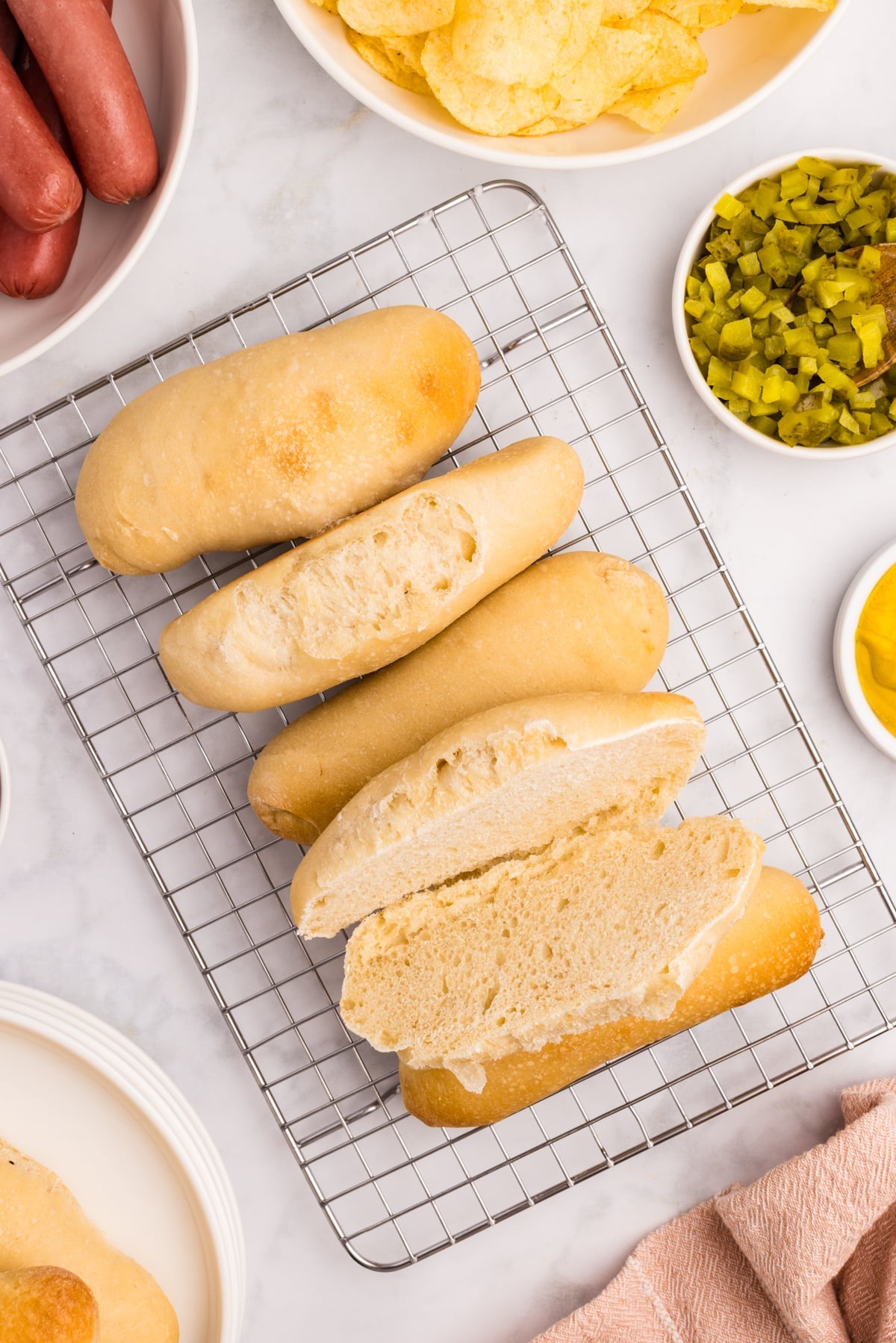 Homemade hot dog buns cooling on a wire rack.