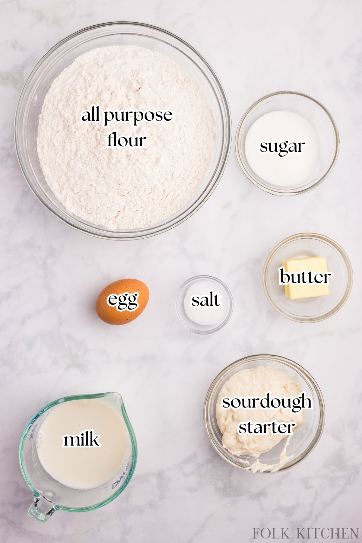 The ingredients needed to make sourdough hot dog buns, including flour, sourdough starter, milk, and butter.