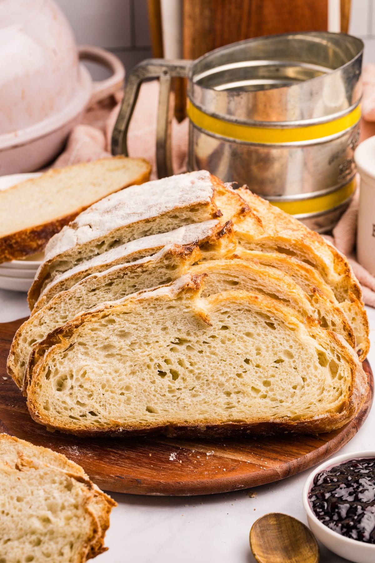 A boule of sourdough bread cut into slices on a cutting board.