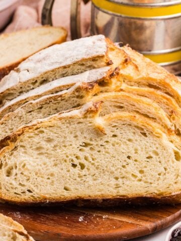 A loaf of sourdough bread cut into slices on a cutting board.